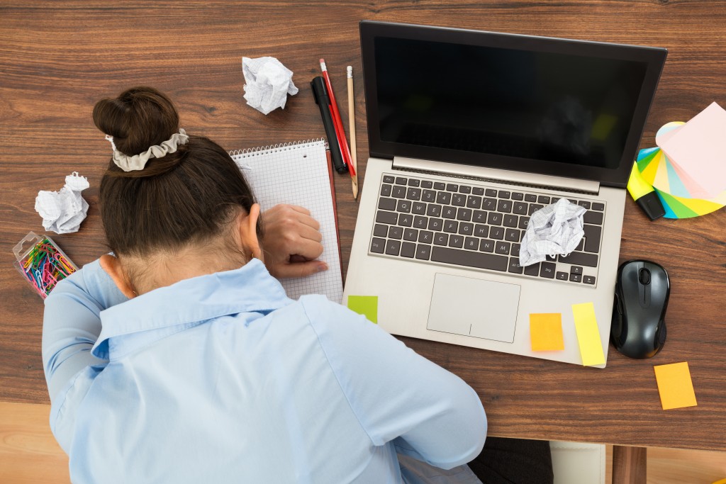 High Angle View Of Businesswoman Doing Head Down On Desk